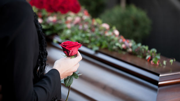 Woman holds rose at coffin